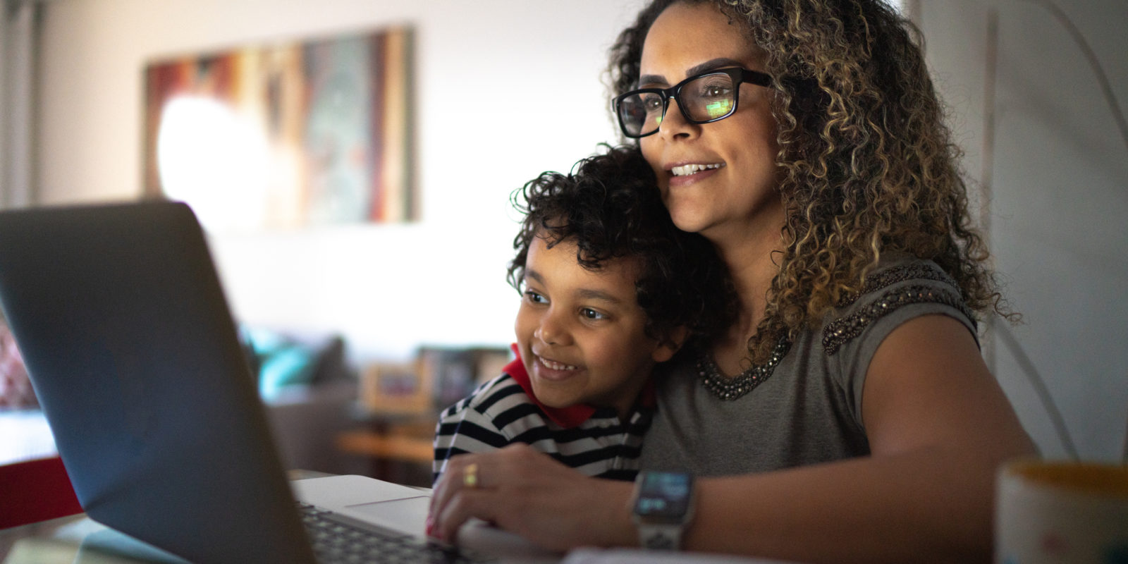 woman and young boy smile at a computer