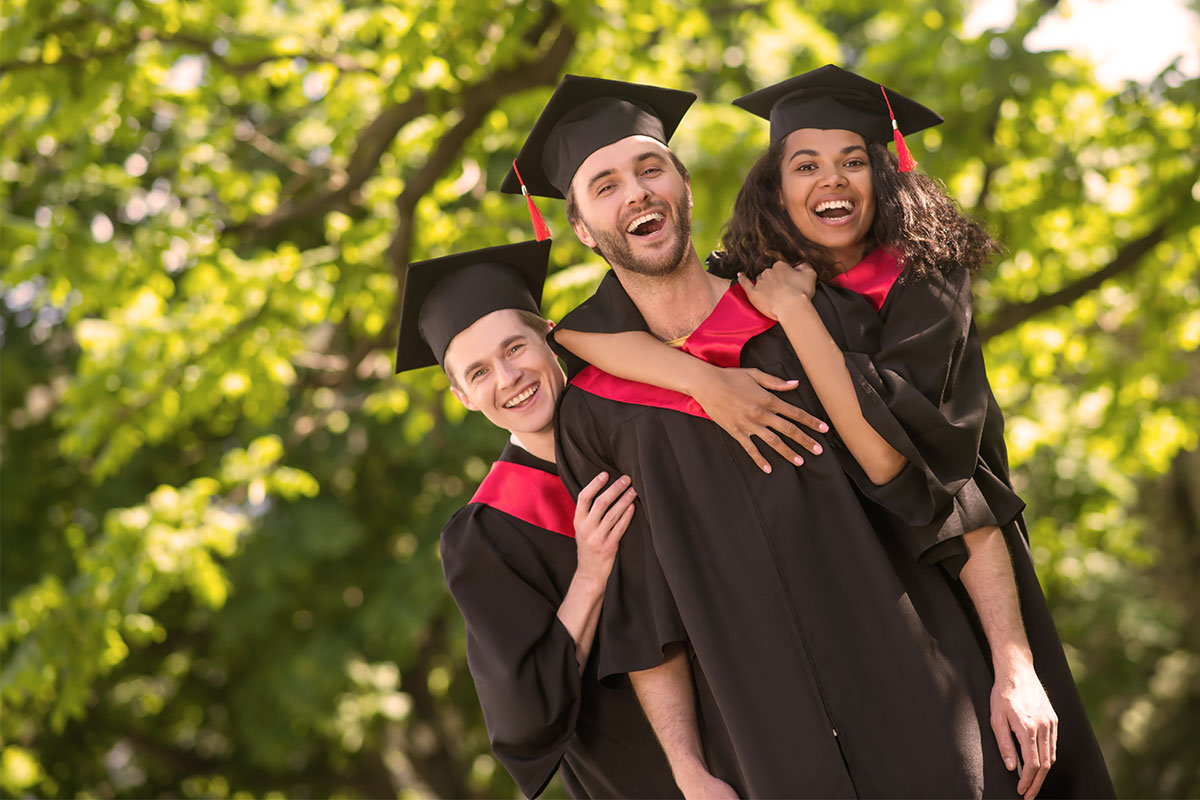 three students laughing in cap and gowns