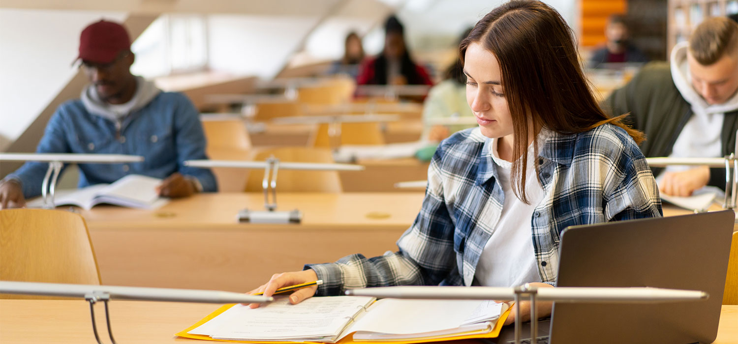 female student doing homework in a library