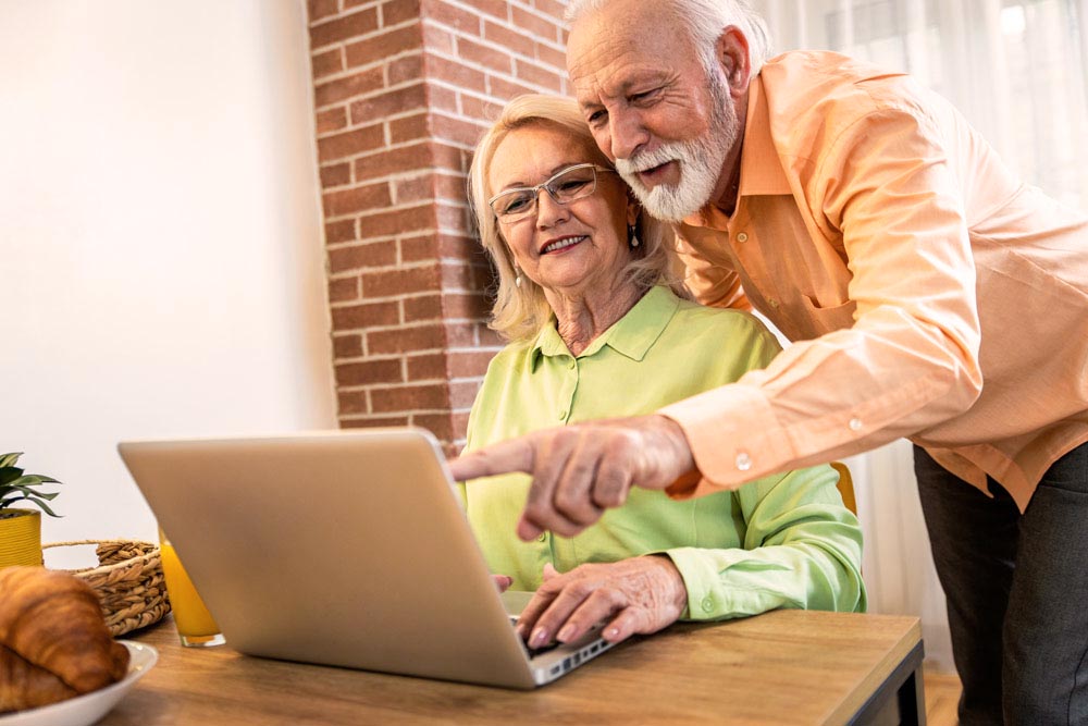 senior couple smiling pointing at laptop