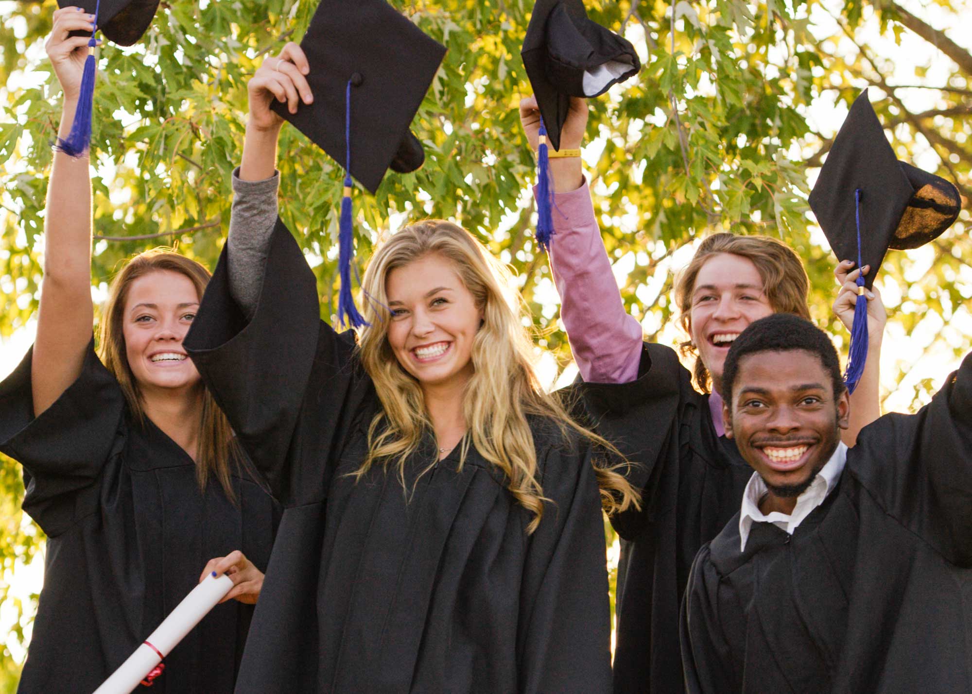 group of graduates holding up caps