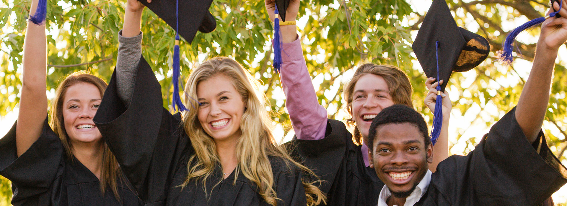 group of graduates holding up caps