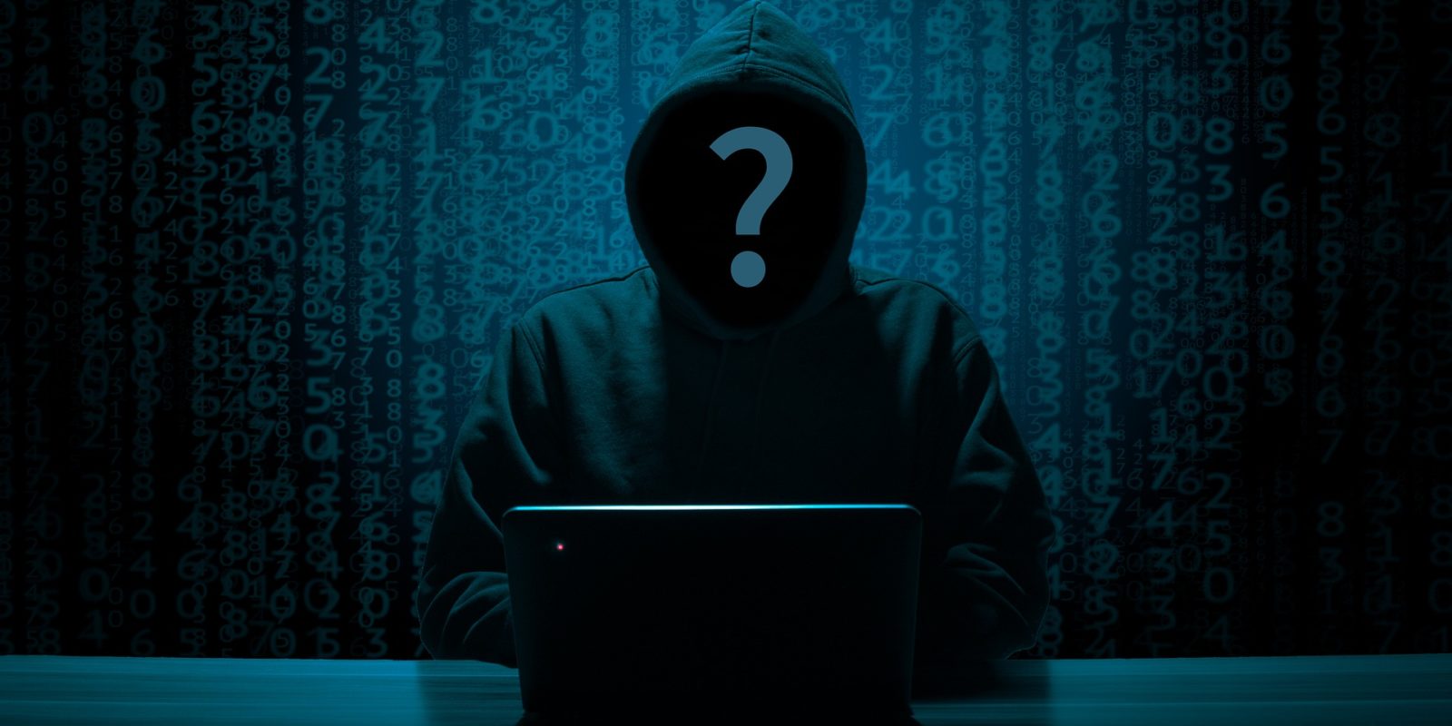 person in a black hoodie and a question mark over their face sits at a laptop in front of a wall of numbers