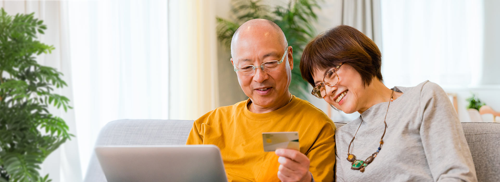 senior asian couple online banking from their living room